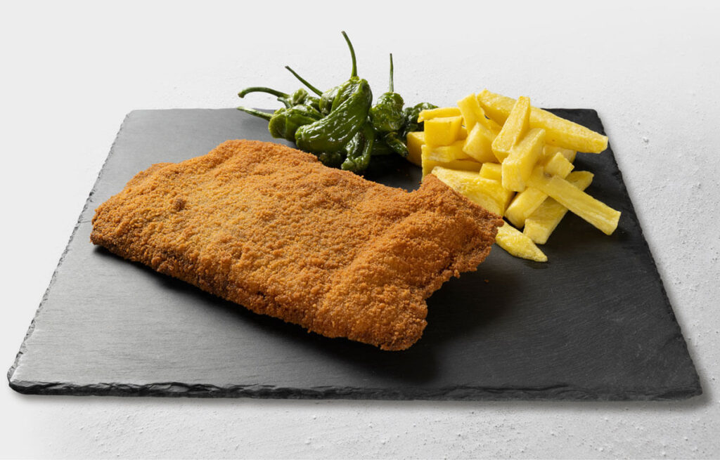 Cachopo asturiano con patatas fritas y pimientos como sugerencia de presentación.