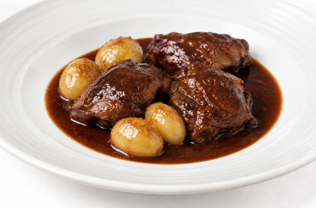 Carrilleras de cerdo guisadas al vino tinto con patatas.