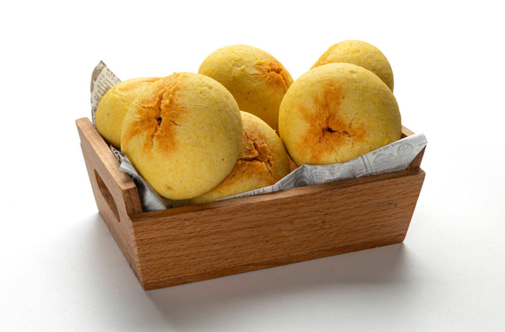 Boroña de maíz rellena de chorizo presentada en cesta de madera.